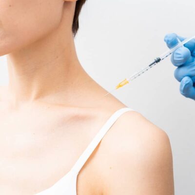Woman receiving a botox injection in her trap area.